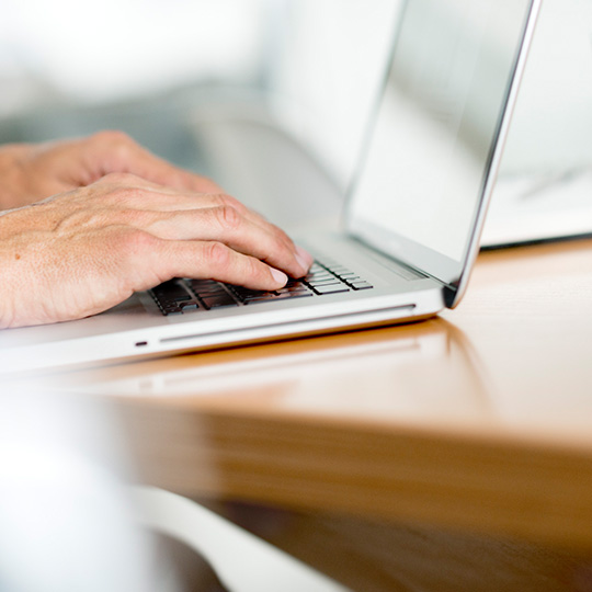 close up of hands working on a laptop
